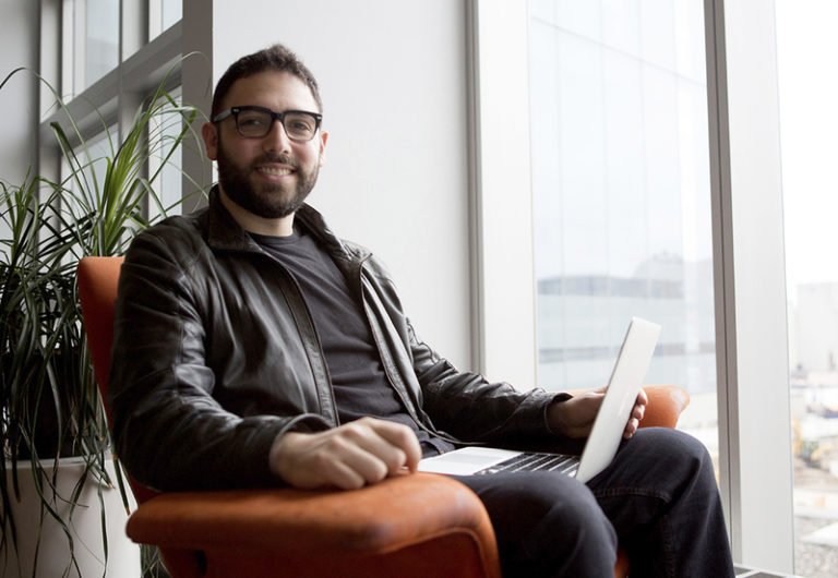 man sitting on a chair holding his laptop