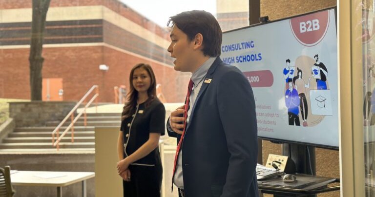 2 students pitching with screen behind them