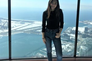 student against a wall of glass overlooking a cityscape