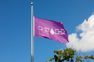 indigenous purple flag waving with blue sky and cloud in background