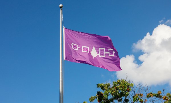 indigenous purple flag waving with blue sky and cloud in background
