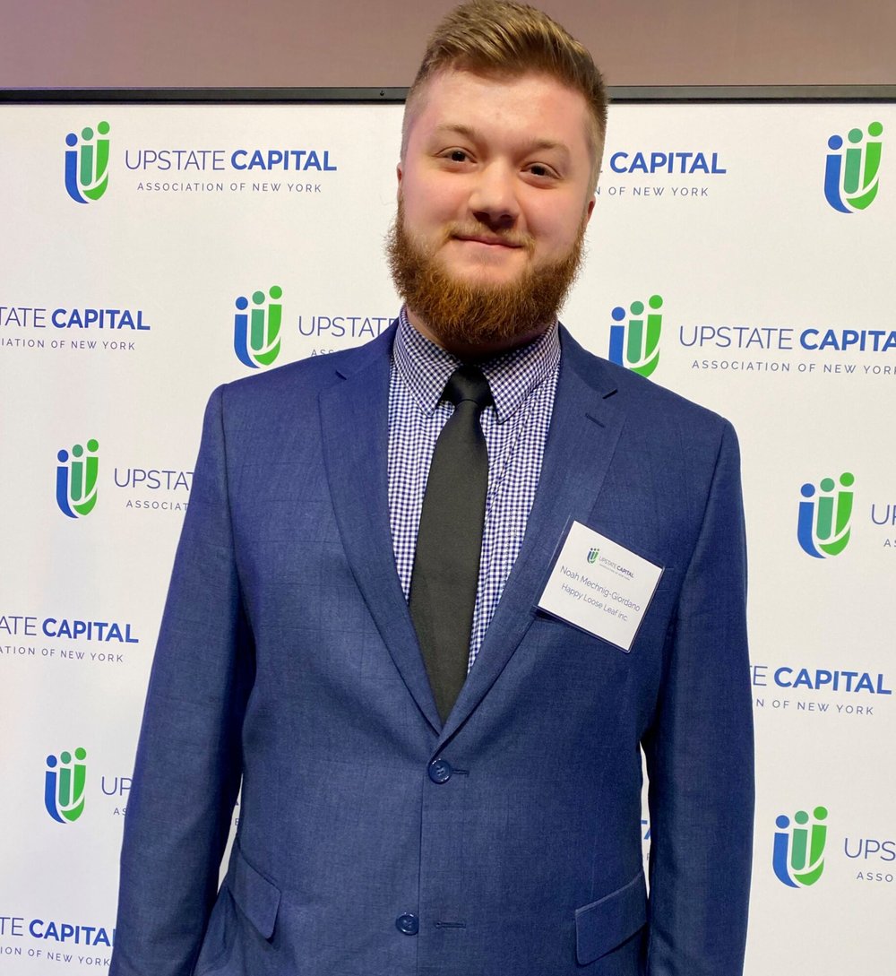 headshot with Upstate Capital Association of New York banner in background