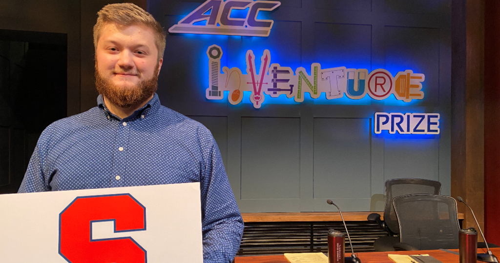 Noah Mechnig-Giordano pose for a photo in fron of ACC InVenture Prize logo