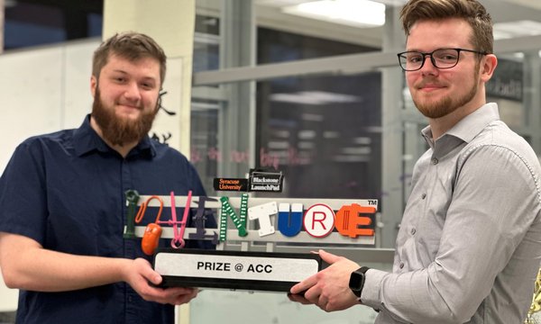 two students holding ACC InVenture prize trophy