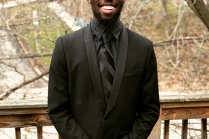 Young man in a suit pose for a photo outside