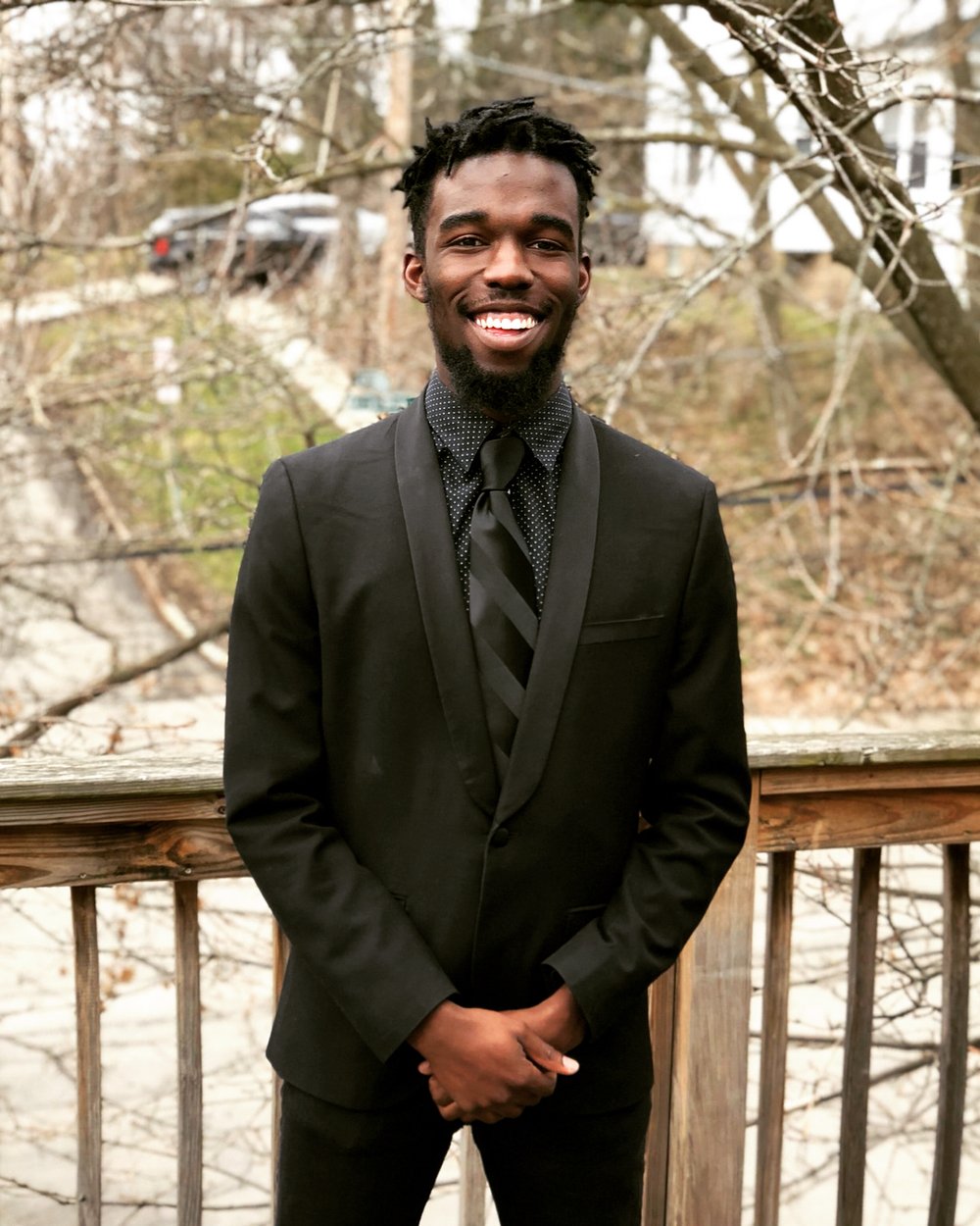 Young man in a suit pose for a photo outside