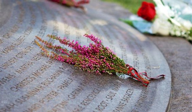 Flowers placed on a gray stone Pan Am Flight 103 memorial engraved with victims' names