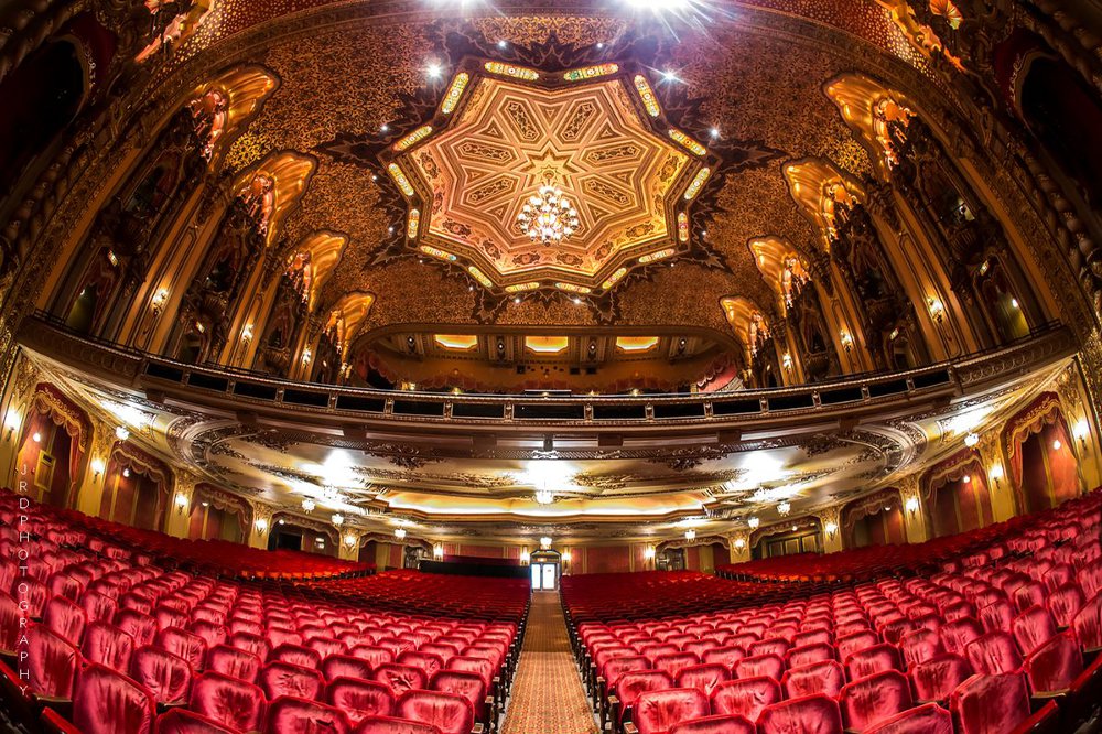 inside of theater with gilded ceiling and red seats