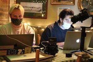 two digital content creators at laptops with video and sound equipment
