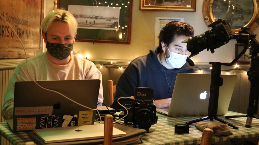 two digital content creators at laptops with video and sound equipment