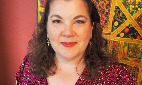 headshot with colorful tapestry behind person