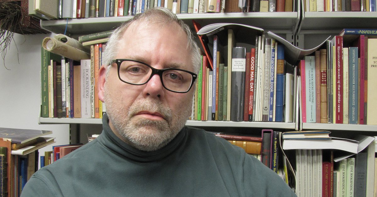 Peter Verheyen sitting in front of a book shelf wearing glasses and a gray turtleneck