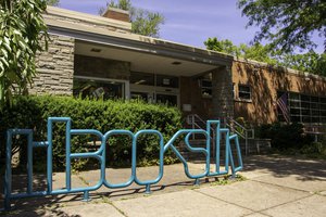 exterior of Petit Branch Library with teal metal bike rack that spells "books" in the Syracuse Westcott neighborhood