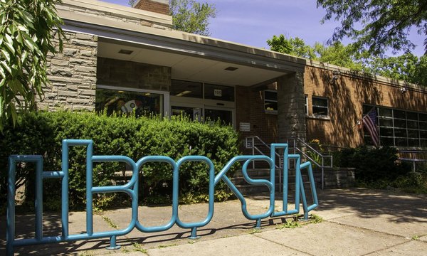 exterior of Petit Branch Library with teal metal bike rack that spells "books" in the Syracuse Westcott neighborhood