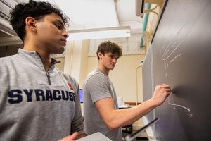 two students writing on chalkboard