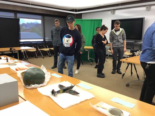 Students standing in classroom with artifacts displayed on tables