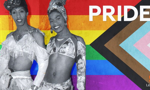 black and white photo of two black drag queens in dresses, with rainbow flag behind them and word PRIDE in reversed white text