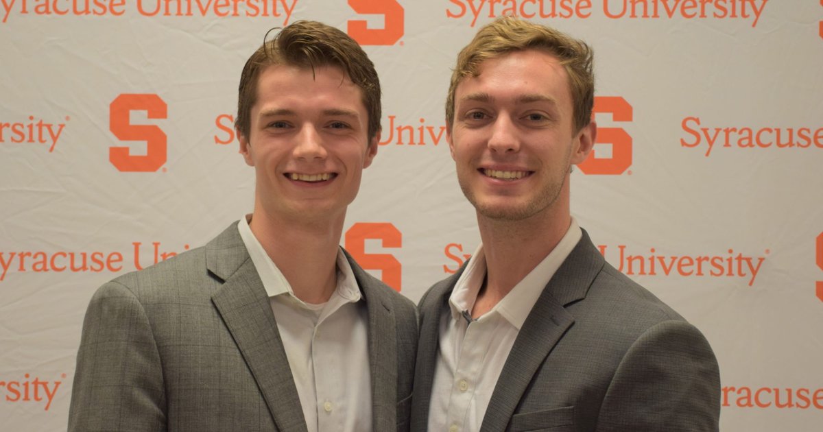 Quinn King and Alec Gillinder in professional attir pose for a photo