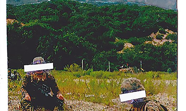 photo of two people on grass with colorful mountain in background