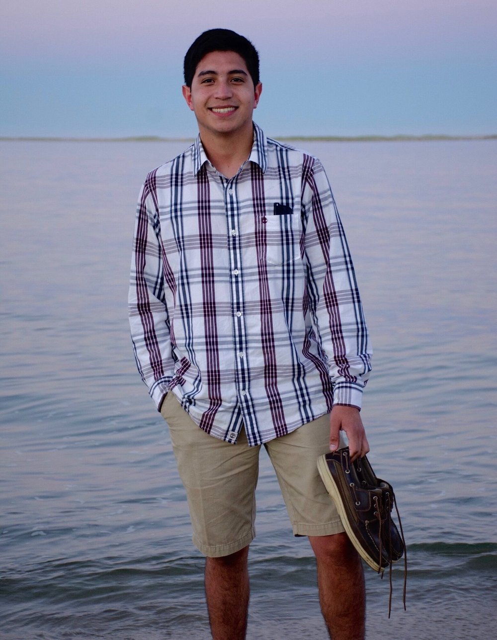 Ricardo Sanchez pose for a photo on the beach, holding his shoe