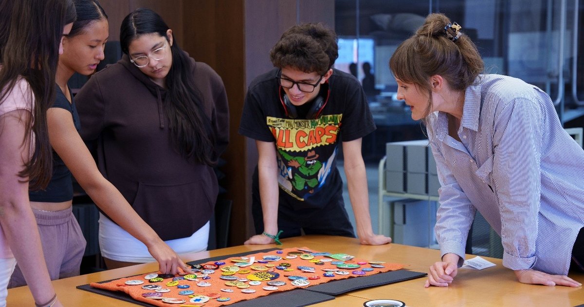 people standing around table looking at buttons on table