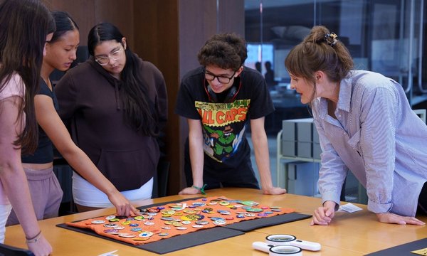 people standing around table looking at buttons on table