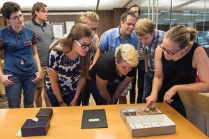 students standing around a table looking at cuneiform tablets.