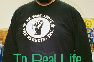 Black man wearing SOYL t-shirt and words In Real Life below