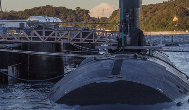 Submarine docked with a ramp and trees in the background
