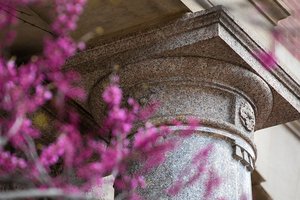 Close up of details on a column at Slocum Hall flanked by purple flowers