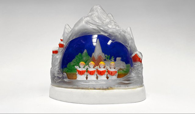 Snow globe with mountain peak top and inside night scene of four carolers singing from books