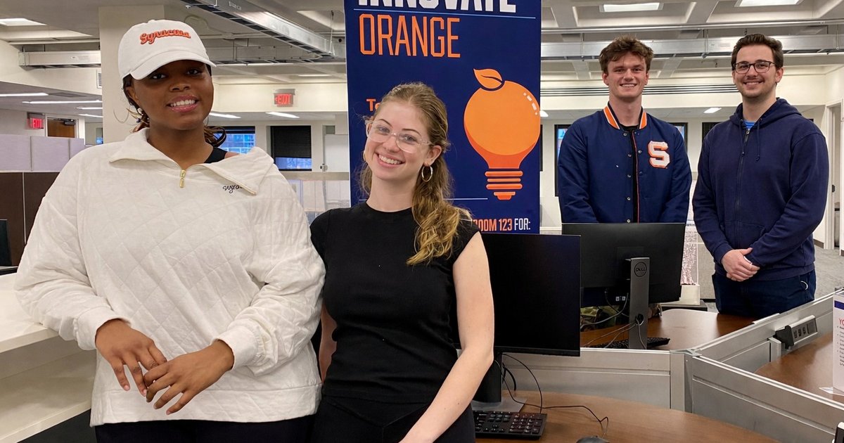 four people standing next to Innovate Orange banner