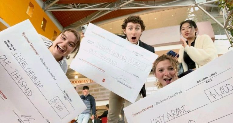 Three students holding oversized check at Martin J. Whitman School of Management at Syracuse University