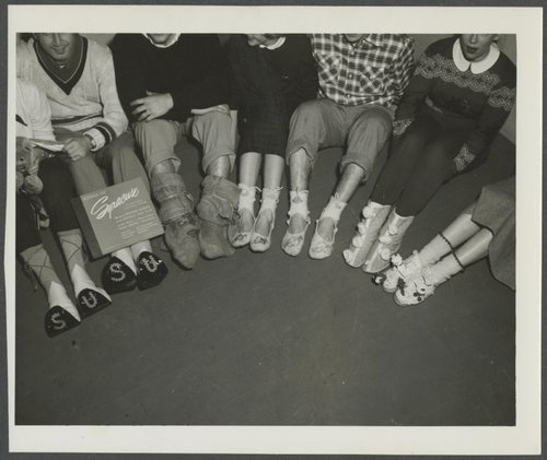 Students show off their homemade stockings. The Stockingfoot Dance, an informal dance at which students traditionally did not wear shoes, included a competition for best stockings. Syracuse University Photograph Collection.