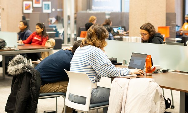 Students working on laptops at long tables on the second floor of Bird Library