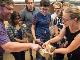 Nicolette Dobrowolski pointing to small medieval book with group of students looking on