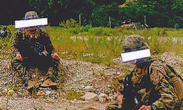 two people in military uniforms on grassy patch with mountain in background
