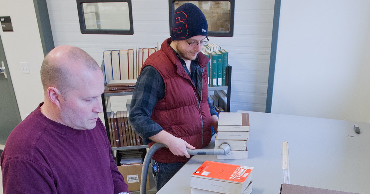 Facility staff handling books with book cart in background