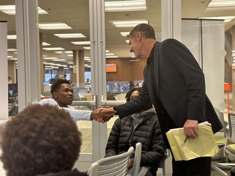 Tim Geannopulos shakes hand with student