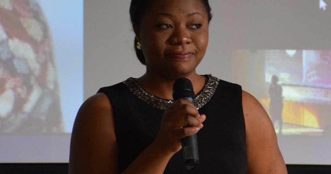 person standing with microphone in front of screen