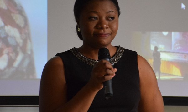 person standing with microphone in front of screen