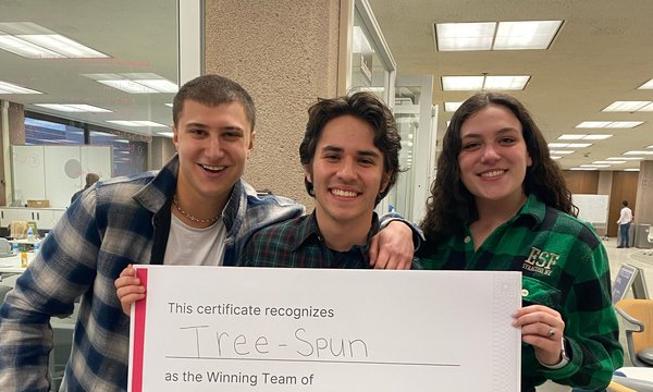 three people holding large white sign