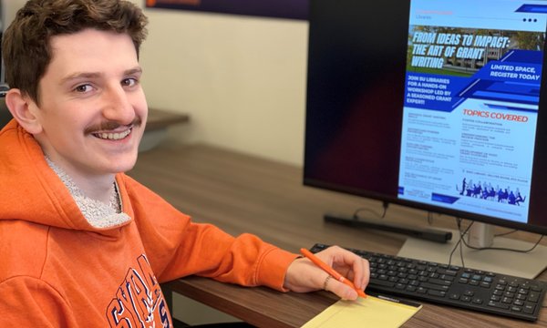 person at computer looking at grants workshop flyer