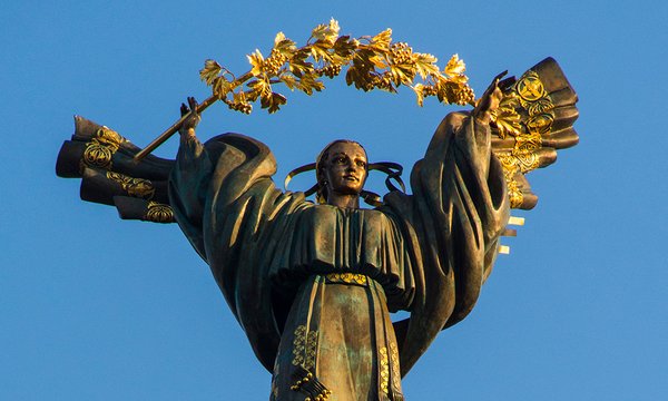 golden statue of person wearing robe with gold wreath above head