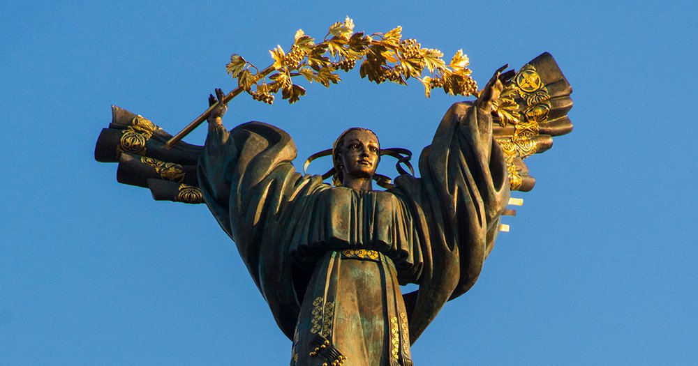 golden statue of person wearing robe with gold wreath above head