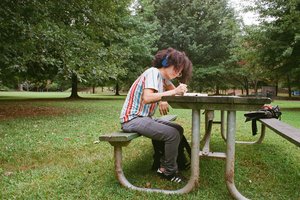 Vanessa Lora sits on a bench at a park with her headphone on