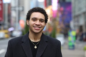 young man on a street smiling into the camera
