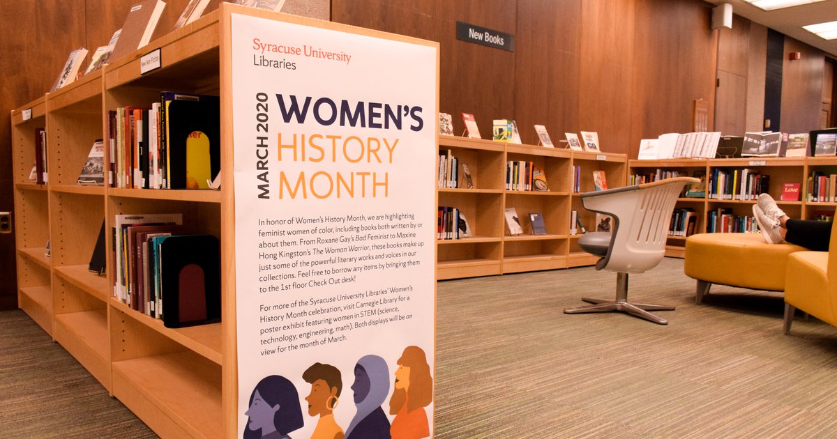 Women's History Month book display with white sign and light wood book shelves