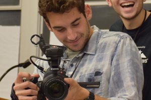 Will DeVito holding a camera, man smiling in the background
