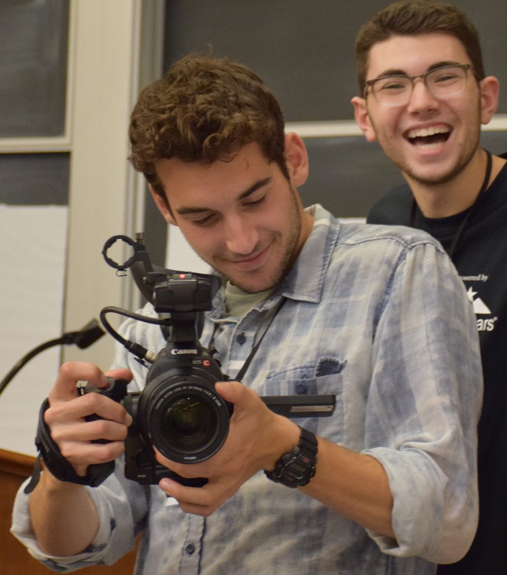 Will DeVito holding a camera, man smiling in the background